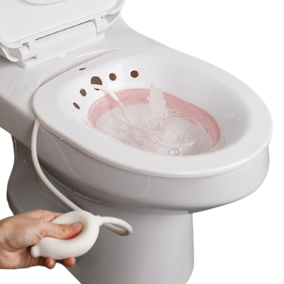 Bidet rétractable avec pompe, montrant le siège et une main utilisant une manette déclencheur près d’un jet d’eau dans la cuvette blanche.